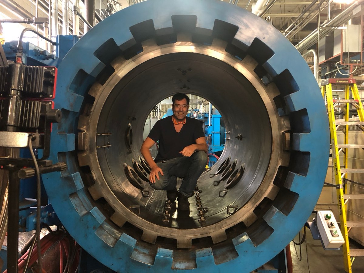The principal of Industry Stewardship crouching inside a large industrial furnace during a plant visit