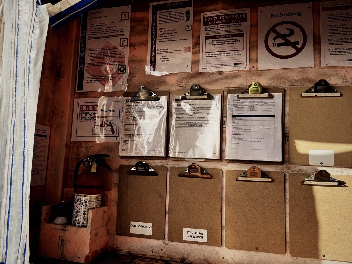Workplace safety board with clipboards, notices and a fire extinguisher