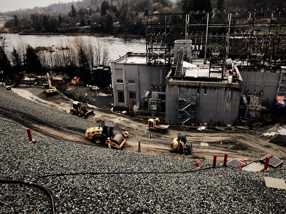Loaders working around a new substation building beside a river