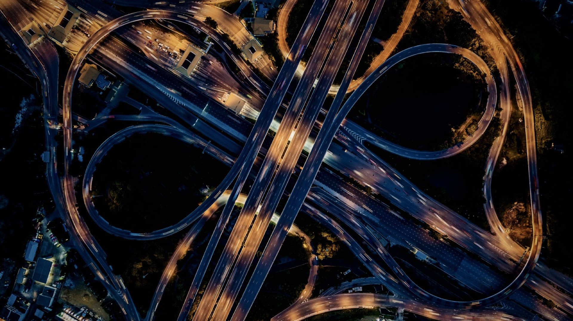 Aerial view of a highway interchange at night, with routes weaving and connecting